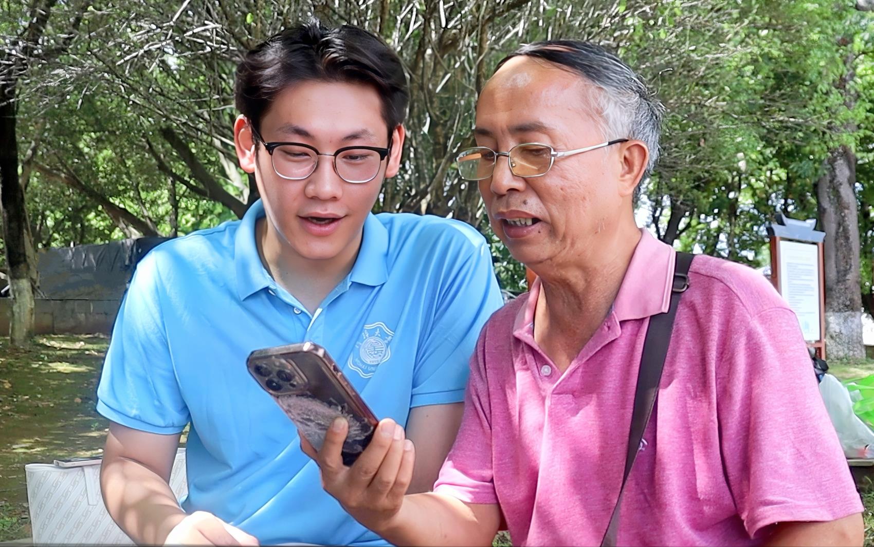 图为实践团成员与当地老人一起学习诵读古诗